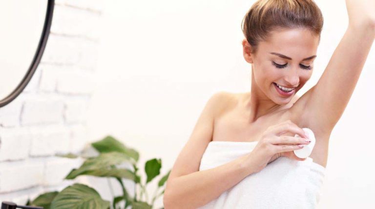 A woman apply aluminum-free deodorant.