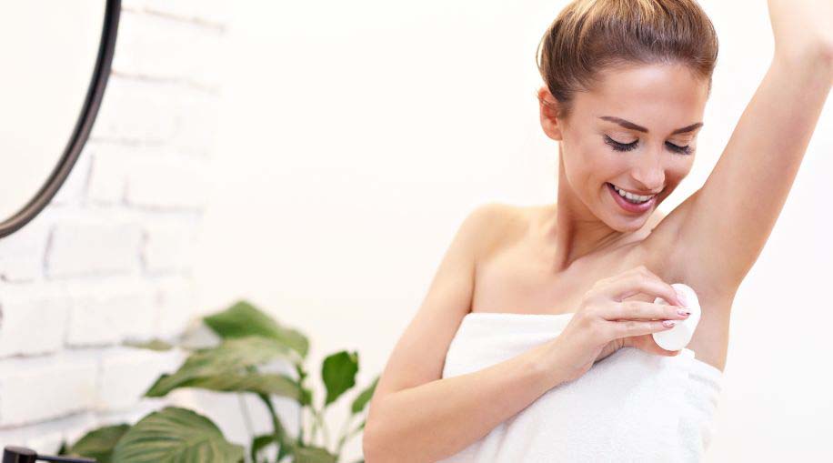 A woman apply aluminum-free deodorant.