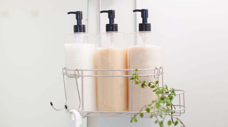 Three bottles of shampoo and conditioner in a bathroom basket.