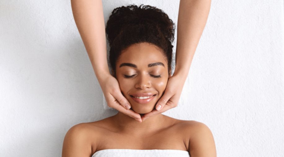 A woman laying on her back, getting a facial massage