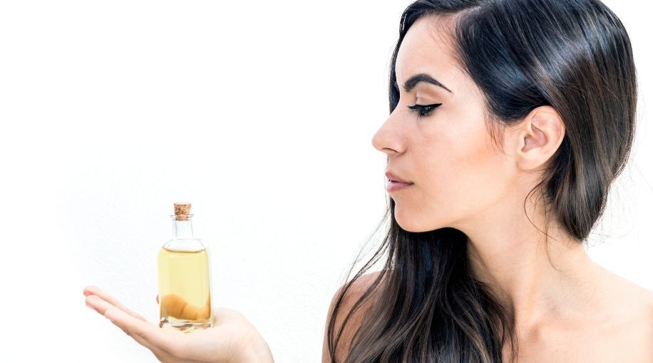 a woman holding a bottle of oil in her right hand