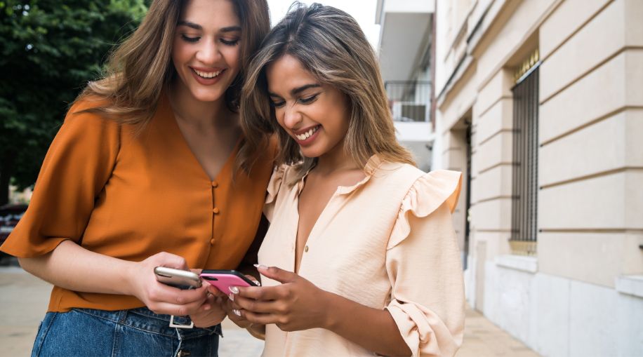 Two women holding and comparing their cell phones.