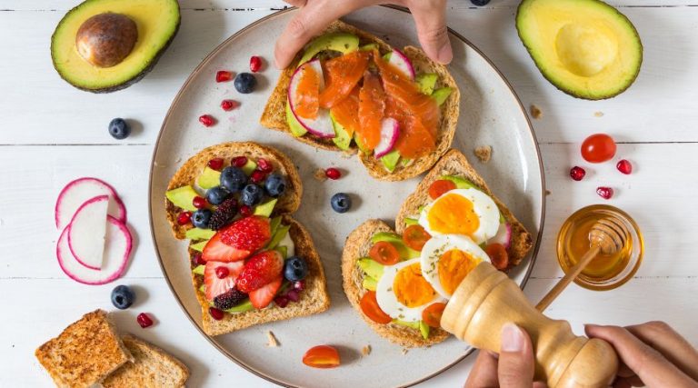 A plate with three pieces of toast, covered in berries, eggs, and other healthy toppings.